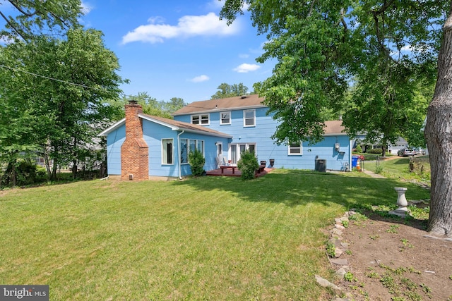 rear view of house featuring fence, a chimney, and a lawn