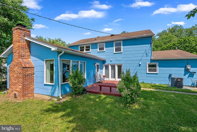 rear view of house with a wooden deck, cooling unit, a chimney, and a lawn