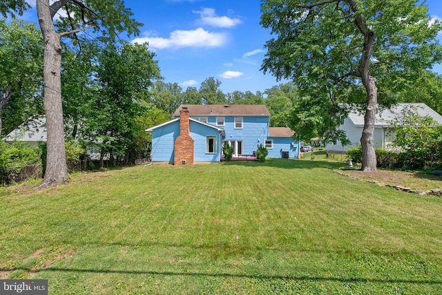 rear view of property featuring a yard and a chimney