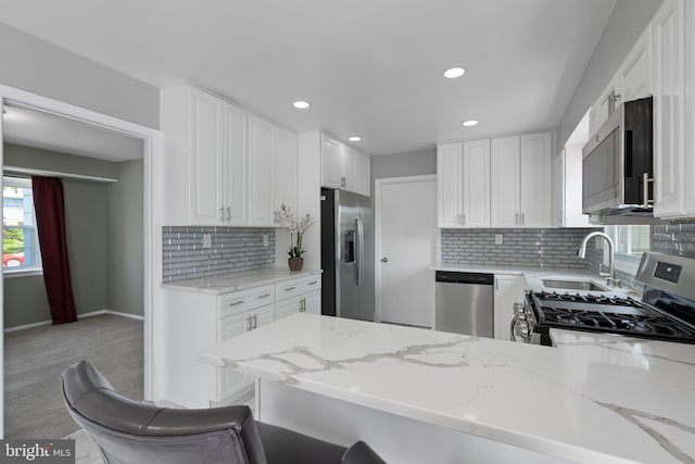 kitchen featuring a healthy amount of sunlight, stainless steel appliances, a sink, and light stone countertops