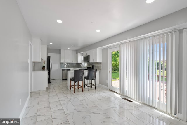 kitchen featuring a kitchen breakfast bar, visible vents, recessed lighting, white cabinets, and appliances with stainless steel finishes