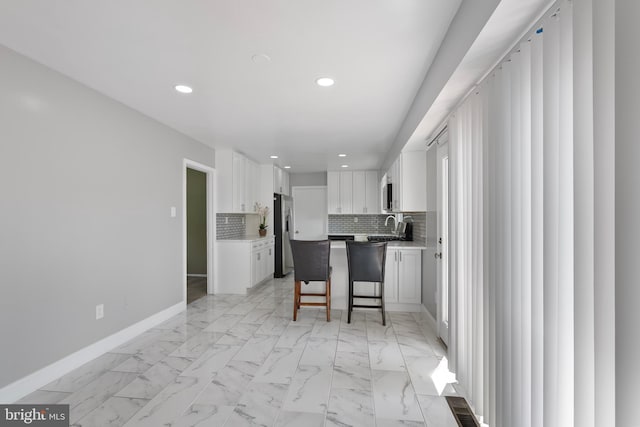 kitchen featuring baseboards, stainless steel fridge with ice dispenser, white cabinetry, and recessed lighting