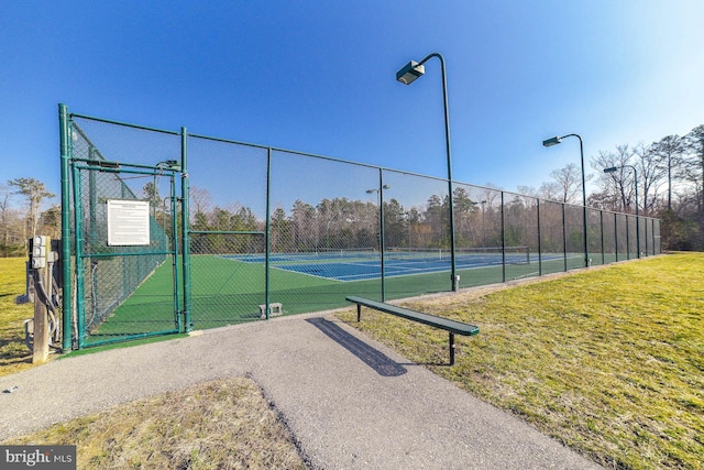 view of sport court with a lawn, fence, and a gate