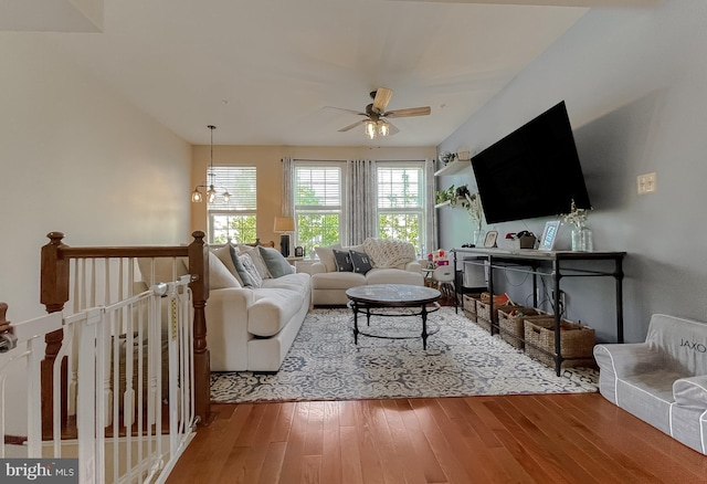 living area with ceiling fan with notable chandelier and wood finished floors