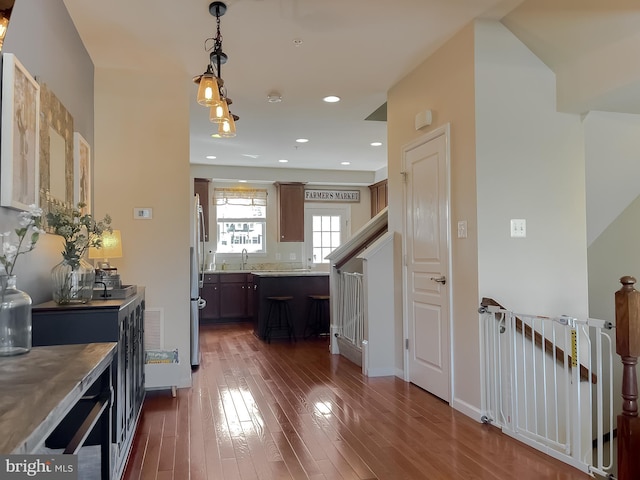 kitchen featuring pendant lighting, freestanding refrigerator, dark wood-style floors, light countertops, and a sink