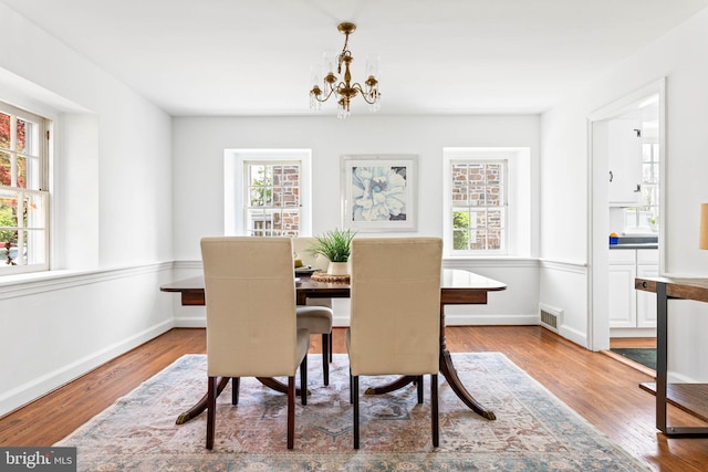 dining area featuring baseboards, a notable chandelier, wood finished floors, and visible vents
