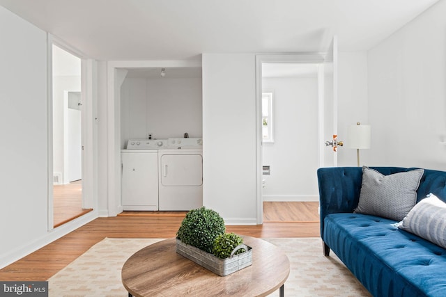 living area with baseboards, light wood-style flooring, and washer and dryer