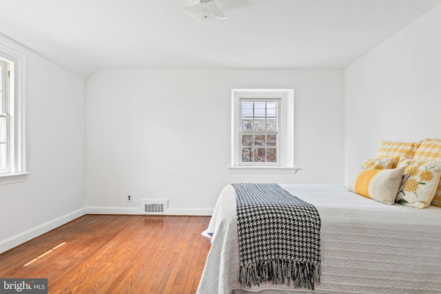 bedroom with visible vents, baseboards, and wood finished floors
