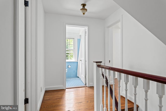 hall featuring baseboards, an upstairs landing, and wood finished floors