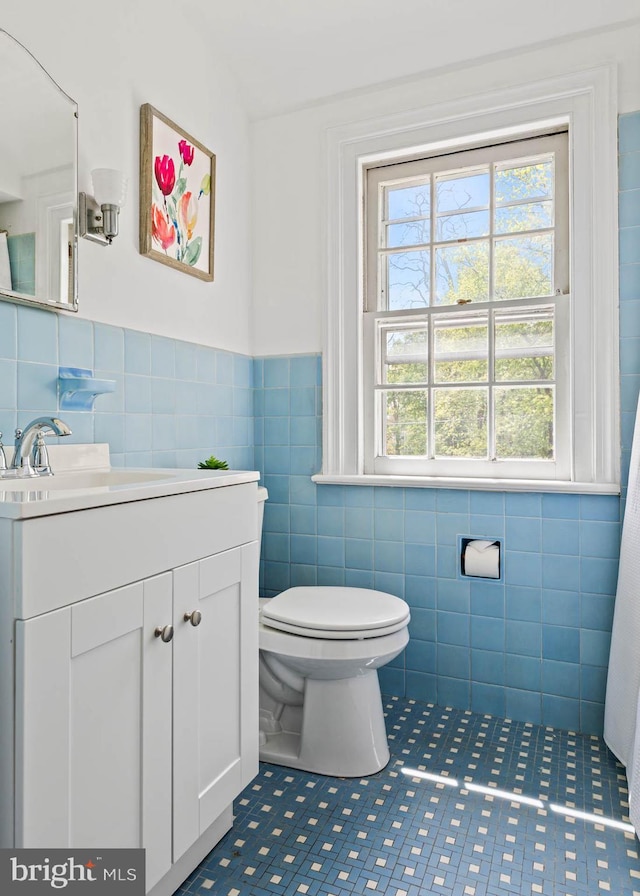 bathroom with tile walls, toilet, tile patterned floors, and a wealth of natural light