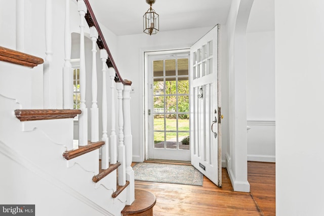 foyer with baseboards, stairs, wood finished floors, and arched walkways