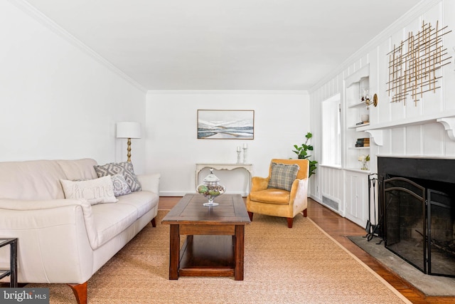 living room with crown molding, a fireplace with flush hearth, wood finished floors, and visible vents