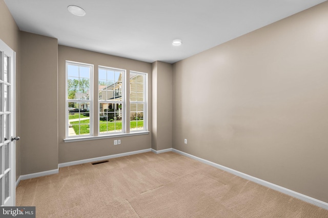 spare room featuring baseboards, visible vents, and light colored carpet