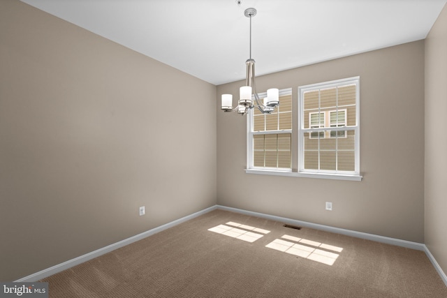 carpeted empty room with an inviting chandelier, visible vents, and baseboards