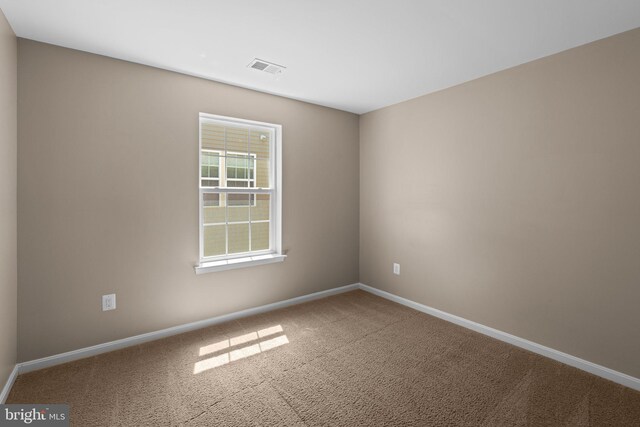 spare room with carpet, visible vents, and baseboards