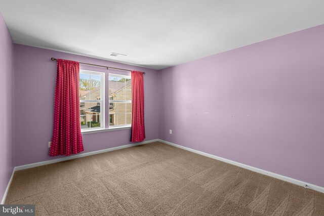 carpeted spare room with visible vents and baseboards