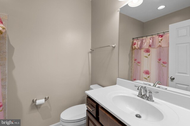bathroom with baseboards, vanity, curtained shower, and toilet