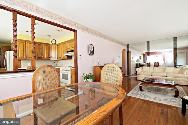 dining area with wood finished floors and arched walkways