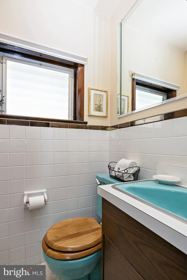 half bathroom with tile walls, toilet, and vanity