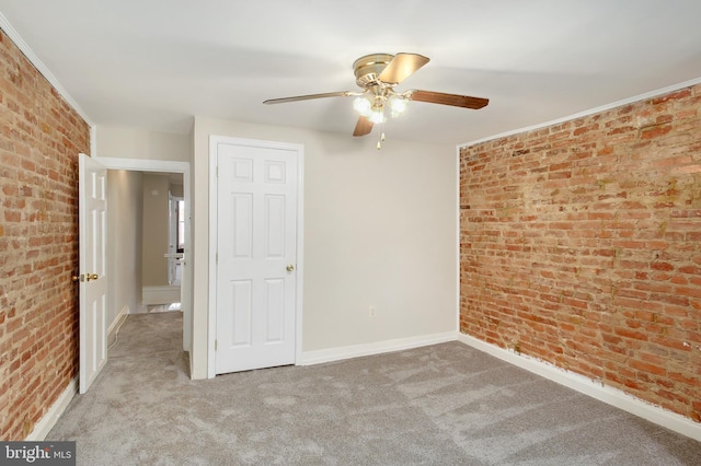 unfurnished bedroom with baseboards, carpet floors, and brick wall