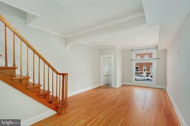 interior space featuring baseboards, ornamental molding, wood finished floors, and stairway