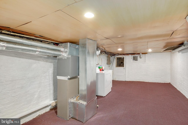 unfinished below grade area featuring carpet flooring, brick wall, washer / dryer, and heating unit