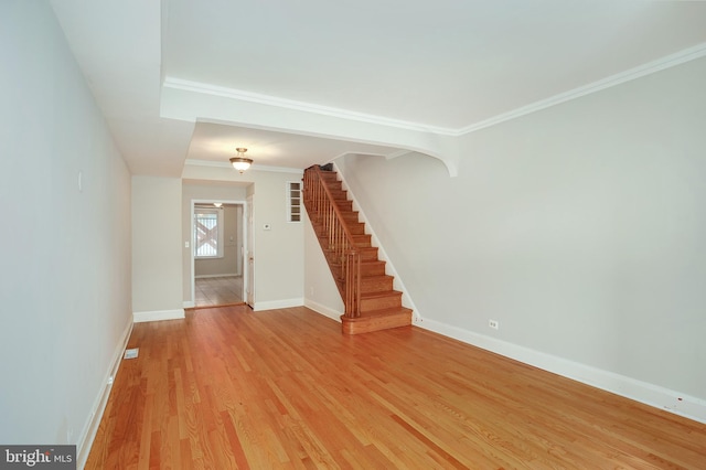 foyer entrance with crown molding, baseboards, light wood finished floors, and stairs