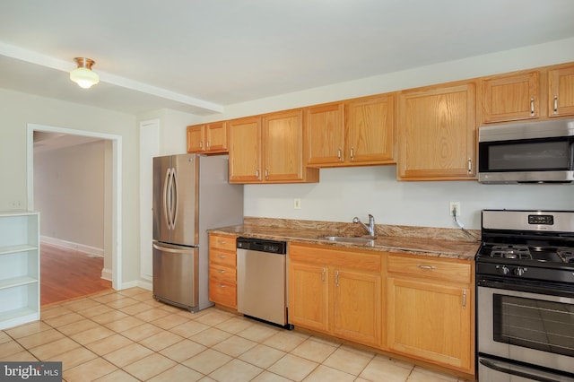 kitchen featuring stainless steel appliances, light stone counters, a sink, and light tile patterned floors