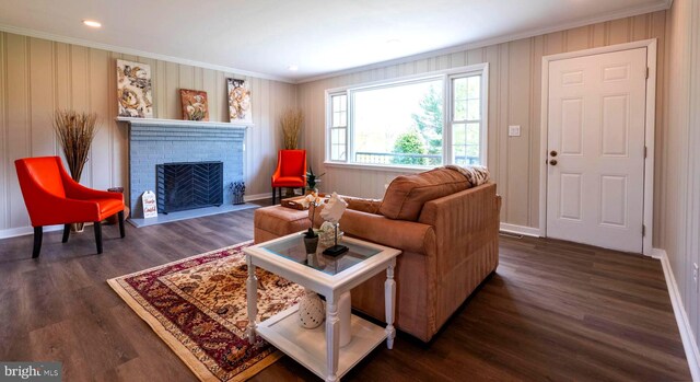 living area with a brick fireplace, baseboards, ornamental molding, and dark wood-style flooring