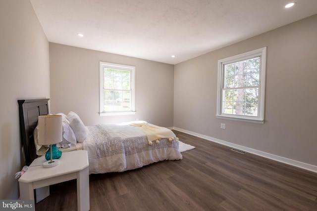 bedroom with visible vents, baseboards, multiple windows, and dark wood-style floors