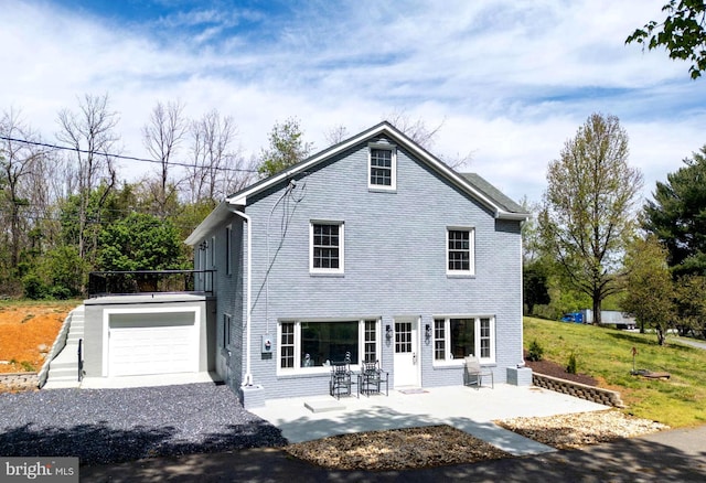 back of property with a garage, gravel driveway, and a patio