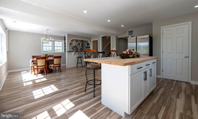 kitchen featuring wood counters, freestanding refrigerator, wood finish floors, and a kitchen breakfast bar