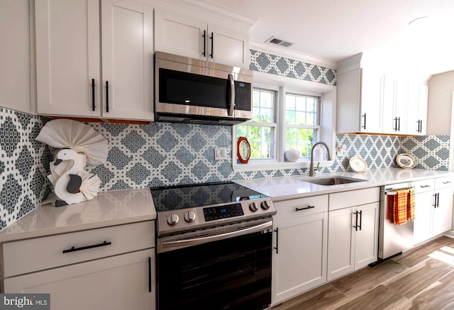 kitchen featuring tasteful backsplash, a sink, light countertops, appliances with stainless steel finishes, and visible vents