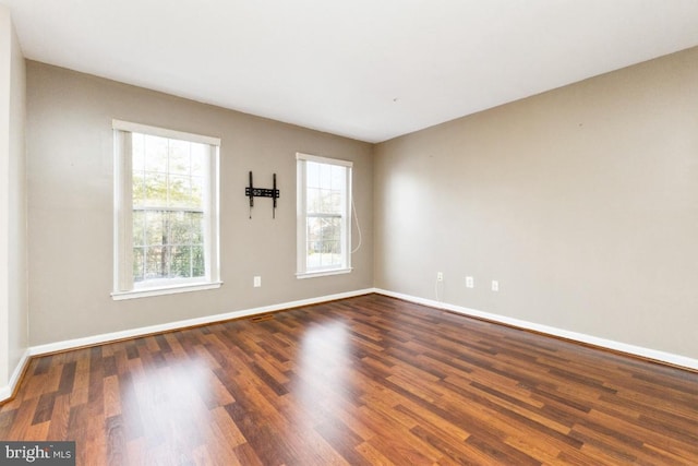 spare room with baseboards and dark wood-style floors