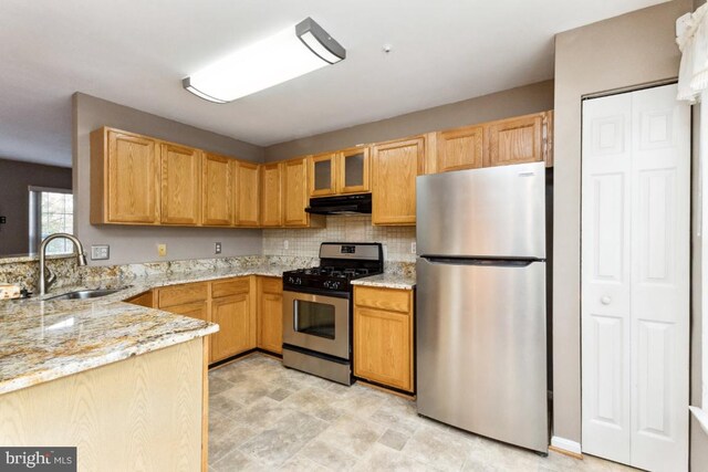 kitchen featuring a sink, glass insert cabinets, stainless steel appliances, under cabinet range hood, and light stone countertops