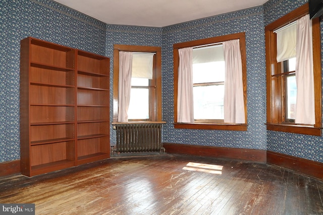 unfurnished room with baseboards, wallpapered walls, radiator, and wood-type flooring