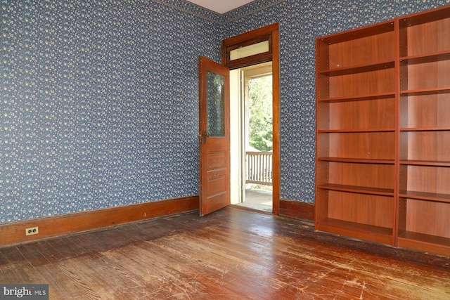 empty room featuring wallpapered walls, wood finished floors, and baseboards