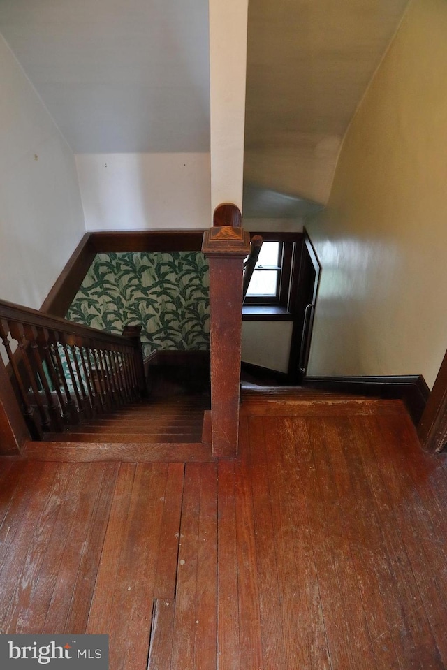 stairway with lofted ceiling, baseboards, and wood-type flooring