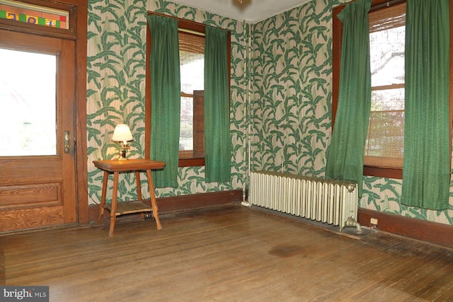 interior space featuring radiator heating unit, wood finished floors, a healthy amount of sunlight, and wallpapered walls