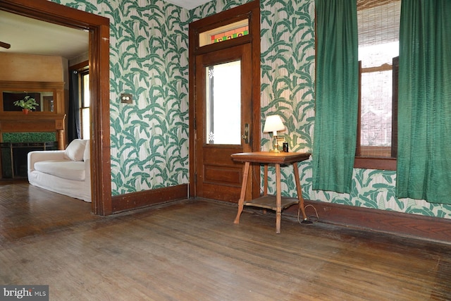 interior space featuring wallpapered walls, wood finished floors, and baseboards