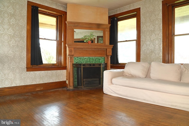 living room with dark wood-style floors, wallpapered walls, and a healthy amount of sunlight