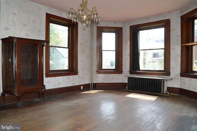 interior space featuring radiator, a notable chandelier, a healthy amount of sunlight, hardwood / wood-style floors, and wallpapered walls