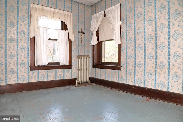 interior space featuring radiator, baseboards, wallpapered walls, and wood-type flooring