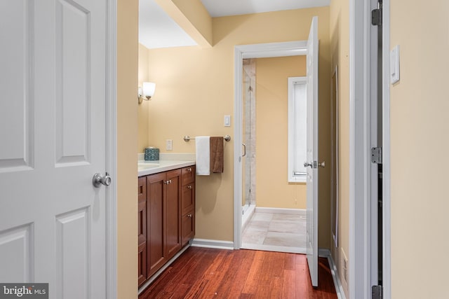 full bathroom with baseboards, wood finished floors, a shower stall, and vanity