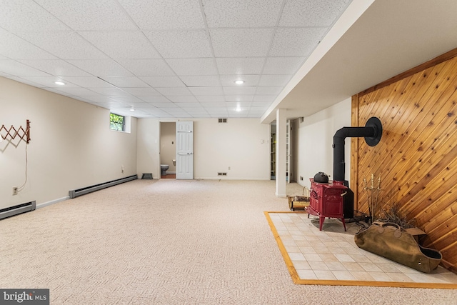 basement with a wood stove, recessed lighting, carpet floors, and a baseboard radiator