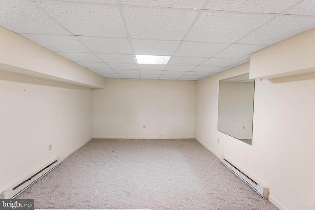 finished below grade area with a paneled ceiling, baseboard heating, and carpet floors