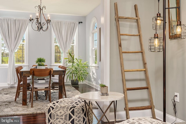 dining space featuring baseboards, wood finished floors, and a chandelier