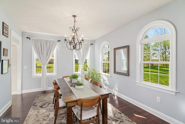 dining area with baseboards, dark wood finished floors, and a chandelier