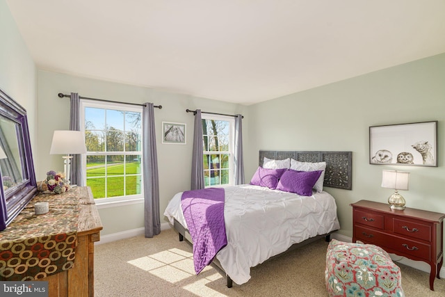 bedroom featuring baseboards, multiple windows, and light colored carpet
