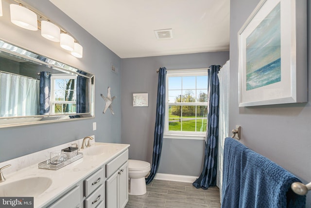 bathroom featuring baseboards, a sink, wood finish floors, and double vanity